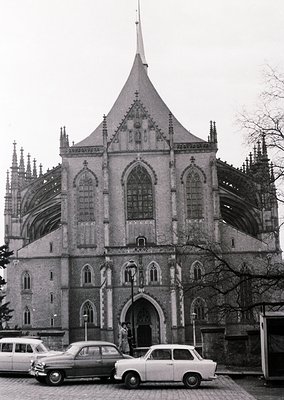 Gothic Revival church façade with pointed arches, ribbed vaulting, and a central spire, likely from the 19th century. Two vin...