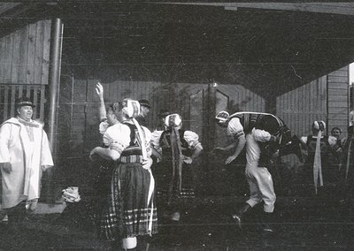 Black-and-white staged scene depicting traditional swordplay, likely a folk or theatrical performance. Central figures in per...