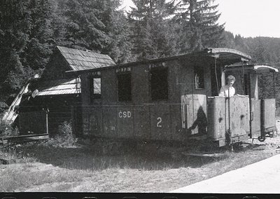 Vintage ČSD (Czechoslovak State Railways) narrow-gauge tourist train car, likely from the **1950s–1970s**, parked beside a ru...