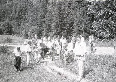 Group of hikers in alpine forest, mid-20th century. Casual attire suggests leisurely outdoor activity, likely a guided trek. ...