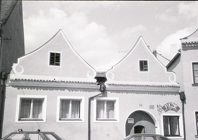 Two-story building with steep gable roofs, decorative cornice, and arched entryway. Signage reads "Pizzeria" in bold letters....