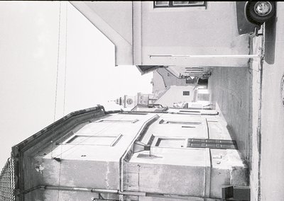 Industrial corridor with exposed concrete and metal railings, featuring a series of small, uniform windows aligned along the ...