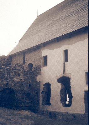 Historic stone-and-plaster building with exposed medieval archway remnants. Gabled roof and small rectangular window suggest ...