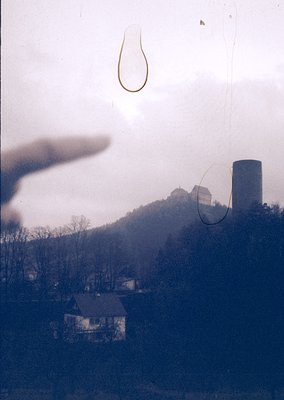 Vintage photograph featuring a blurred, foggy landscape with a lone industrial smokestack and distant castle ruins. Overlaid ...