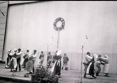 Group of women in traditional folk attire performing a choreographed dance on an outdoor stage, likely Eastern European . Dec...