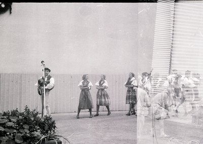 Black-and-white group performance featuring a man playing a stringed instrument (likely a bandura) and women in traditional f...