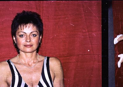 Portrait of a woman in a sleek, black-and-white striped tank top against a red velvet backdrop, likely a 1970s–1980s event or...
