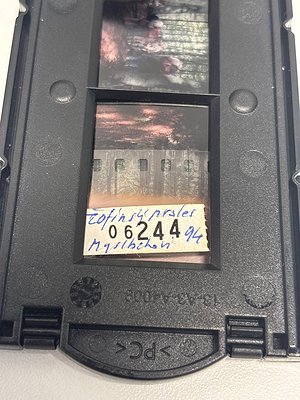 Vintage 35mm film strip (Kodachrome) with handwritten label "06244" and "Mystic Rock" in Cyrillic, showing a coastal scene wi...