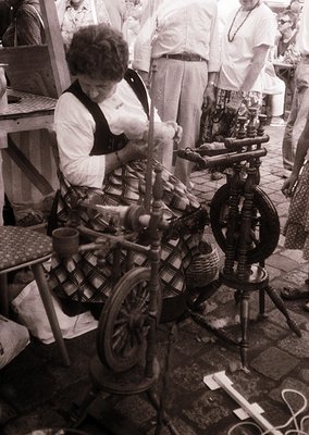 Traditional hand-spinning wheel in use, likely mid-20th century. Woman operates vintage spinning equipment with wool, surroun...
