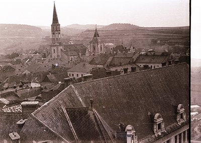 Vintage sepia-toned aerial view of a European village with distinct church spires and tiled rooftops, likely early 20th centu...