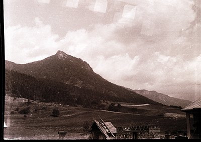 Vintage sepia-toned landscape featuring rugged mountain terrain with sparse vegetation. Foreground includes a small wooden st...