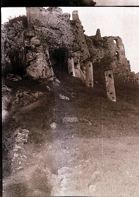 Ruined medieval stone fortress with crumbling walls and arched openings, set on rocky terrain. Likely Eastern European, 12th–...