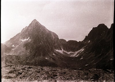 Early 20th-century sepia-toned alpine peak with jagged ridges and snow patches, likely European Alps. Dramatic glacial valley...