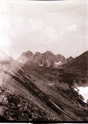 Vintage black-and-white alpine landscape showing jagged peaks and snow patches, likely from mid-20th century. Dramatic lighti...