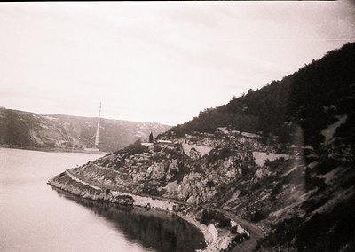 Vintage black-and-white coastal scene featuring a rocky promontory with a small, elevated structure—likely a lighthouse or ch...