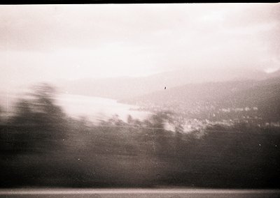 Vintage monochrome shot of motion blur from a moving vehicle, likely a train or bus, capturing a blurred landscape. Distincti...