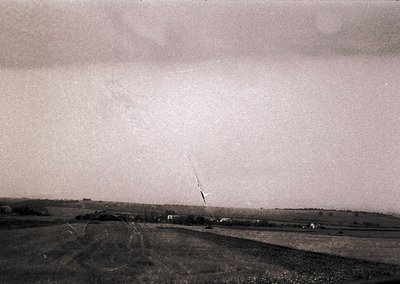 Vintage aerial view of rural landscape with low-lying clouds and rolling terrain. Distinctive diagonal power line cutting thr...