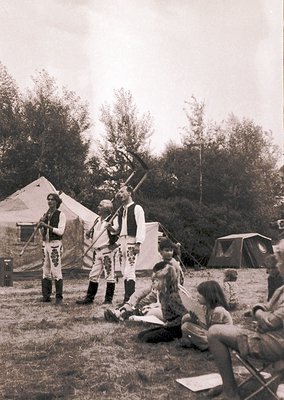Vintage outdoor reenactment scene featuring three men in traditional Balkan military attire (19th-century style) with rifles ...