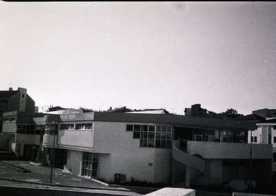 Mid-century Brutalist-style building with raw concrete facade, curved balconies, and large rectangular windows. Urban setting...