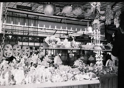 Vintage black-and-white display of handcrafted ceramic and glassware, likely from a 20th-century artisan fair or market stall...