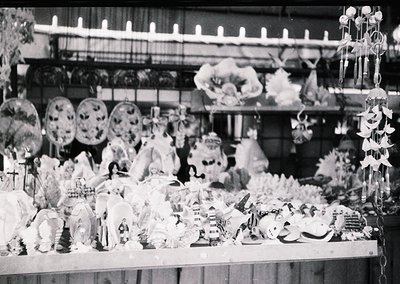 Vintage black-and-white display of ornate holiday decorations—elaborate wreaths, feathered ornaments, and handcrafted figurin...