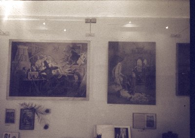 Vintage-style wall featuring two framed classical paintings depicting historical/religious scenes. Left: chaotic battle or si...