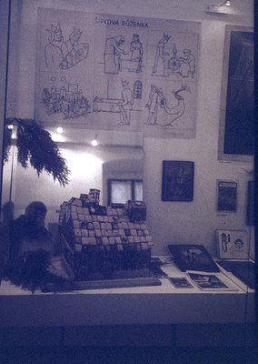 Vintage interior featuring a stacked brick display case with framed illustrations titled *"Šípková Růženka"* (Cinderella-insp...