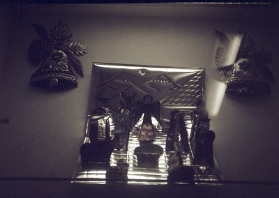 Vintage framed mirror with ornate metal frame featuring geometric patterns. Decorative wall bells and bird motifs flank the r...