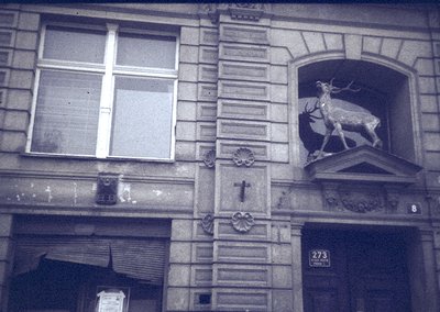 Black-and-white facade of a European building (likely 19th–early 20th century) featuring ornate stonework: a relief deer scul...
