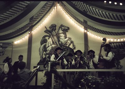 Vintage band performing under a decorative canopy with a mural of a knight on horseback. Stage adorned with string lights and...