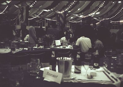 Indoor restaurant scene with string lights overhead, showcasing mid-20th-century dining culture. Round tables with place sett...