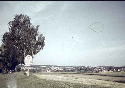 Vintage sepia-toned roadside sign reading **"CODINE"** (likely a brand) with a crown emblem, set against a flat, open landsca...