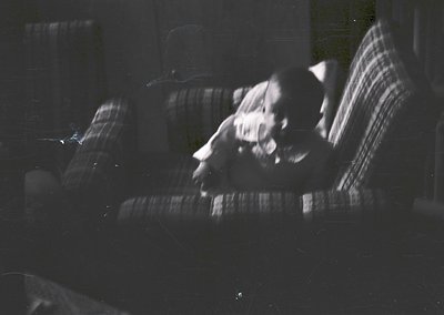 Vintage black-and-white photo of a person reclining on a striped armchair, holding a cigarette. Soft focus and grainy texture...
