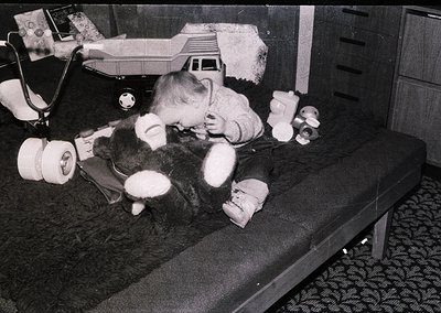 A child in a 1960s-70s hospital gown plays with a toy on a metal bed, surrounded by medical equipment like a stethoscope and ...