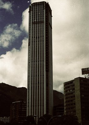 Iconic Brutalist skyscraper with vertical concrete ribs, likely the **Torre Velasca** in Milan, Italy. Built 1958–1960 by BBP...
