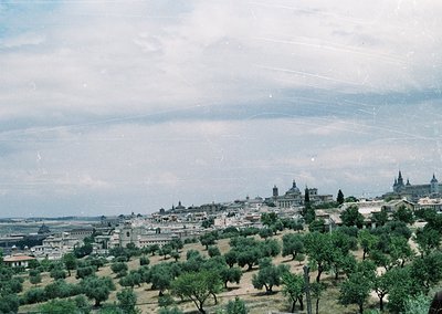 Vintage aerial view of Madrid’s skyline with lush olive groves in foreground. Distinctive domes of the Royal Palace and surro...