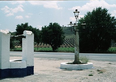 Vintage roadside scene featuring a vintage-style streetlamp with dual lanterns on a concrete base, paired with a concrete pub...