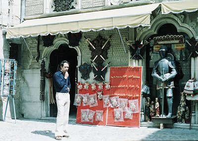 Vintage street vendor stall showcasing handcrafted leather goods, swords, and souvenirs in a historic European courtyard. Man...