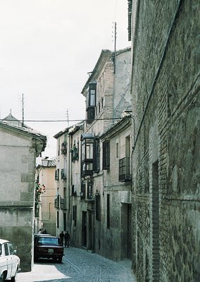 Narrow cobblestone street flanked by aged stone buildings with wooden shutters and balconies. Classic European architectural ...