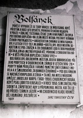 A black-and-white commemorative plaque mounted on a stone wall, detailing historical events in **Bolfánek**, Czech Republic. ...