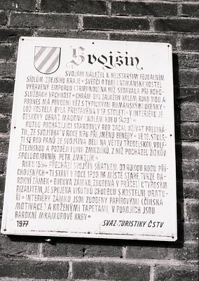 A white informational plaque mounted on a brick wall, detailing the history of **Svijnín Castle** in Czechia. The text (Czech...