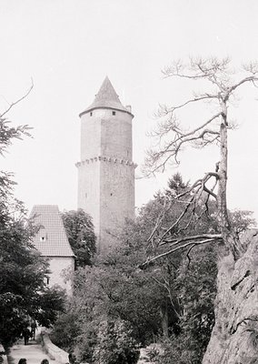 Historic stone watchtower with conical roof, surrounded by dense foliage and rocky terrain. Likely Eastern European medieval ...