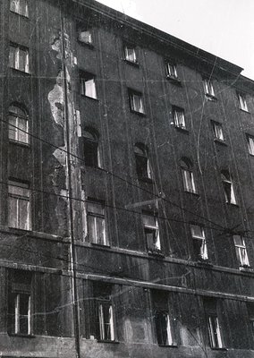 Mid-century Soviet-era apartment block under renovation, featuring scaffolding and exposed brickwork. Symmetrical windows wit...