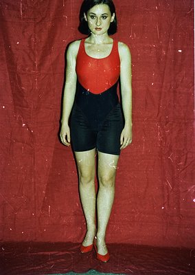 Vintage mannequin in bold 1960s-style swimsuit: red top with black paneling, black shorts, and red shoes. Stylized pose on re...