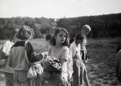 Group of children in outdoor setting, mid-20th century. Central figure holds a basket, others gather around. Casual clothing ...