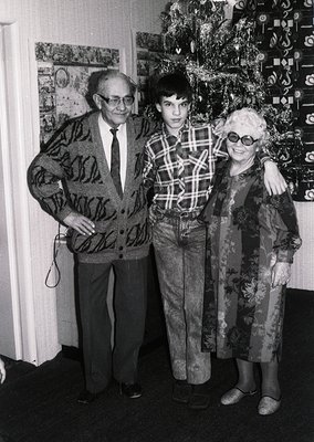 Family portrait from the **1970s**, featuring a man in a patterned sweater and tie, a young boy in plaid shirt and bell-botto...