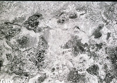 Close-up of heavily eroded, cracked stone surface with granular texture, likely marble or limestone. The weathering suggests ...