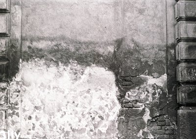 Vintage sepia-toned photograph showing a collapsed stone wall and debris, likely from an earthquake or structural failure. Th...