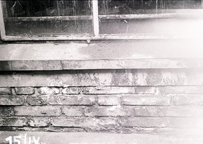 Close-up of weathered brick facade with cracked plaster and exposed mortar, likely from early-to-mid 20th century architectur...
