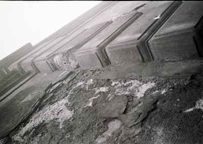 Close-up of weathered concrete ledge with exposed rebar and cracked surface, likely part of an industrial or urban structure....